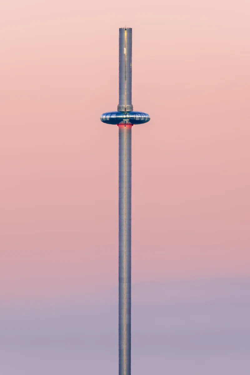 Brighton i360 tower centred against a soft pastel sky, with the observation pod mid-ascent in a minimal composition.