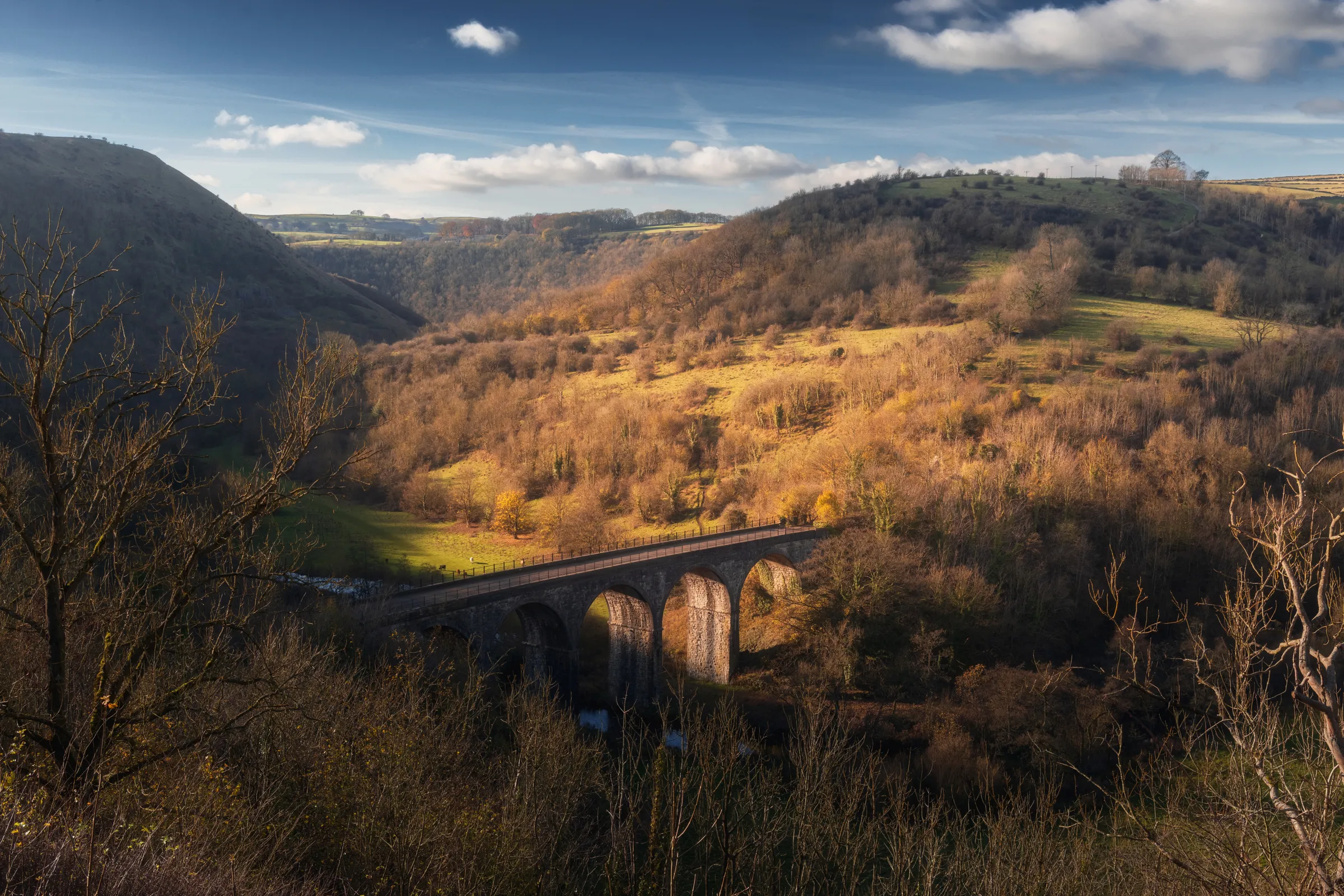 Monsal Head Viaduct crossing a valley in the Peak District, lit by low autumn sunlight with rolling hills beyond.
