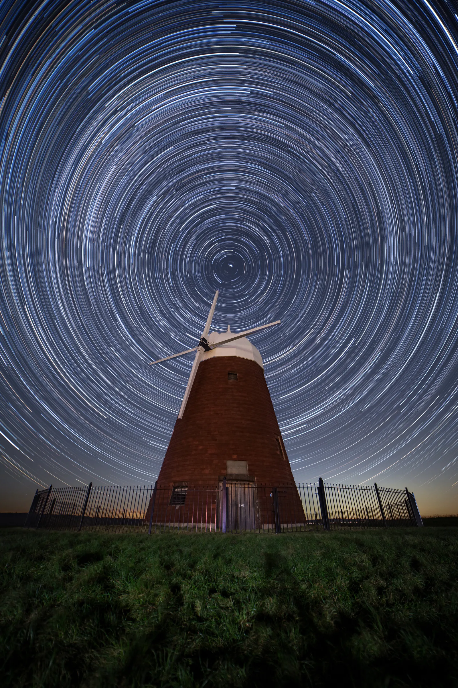 Halnaker windmill beneath dense circular star trails, with concentric arcs centred above the structure.