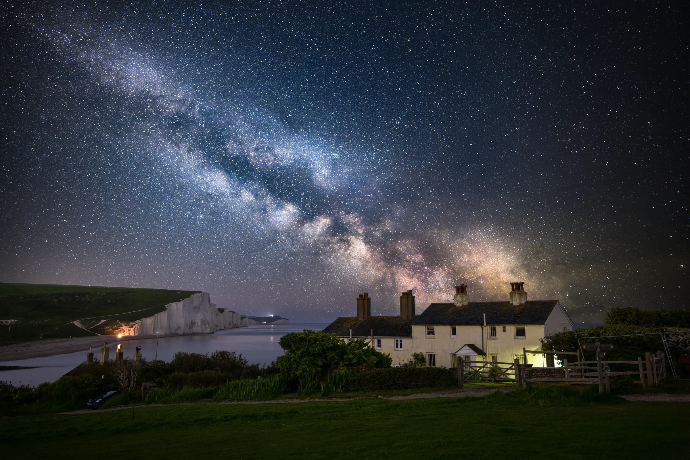 The Milky Way arching over the Coastguard Cottages at Cuckmere Haven with the Seven Sisters cliffs beyond