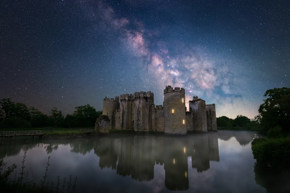 The Milky Way rising above Bodiam Castle reflected in the still waters of the moat