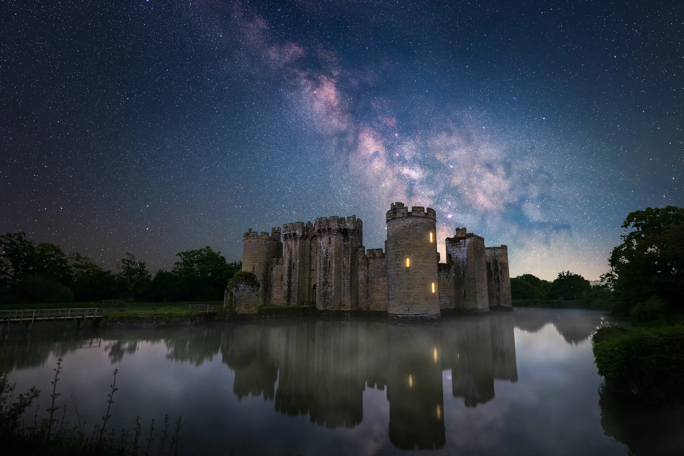 The Milky Way rising above Bodiam Castle reflected in the still waters of the moat