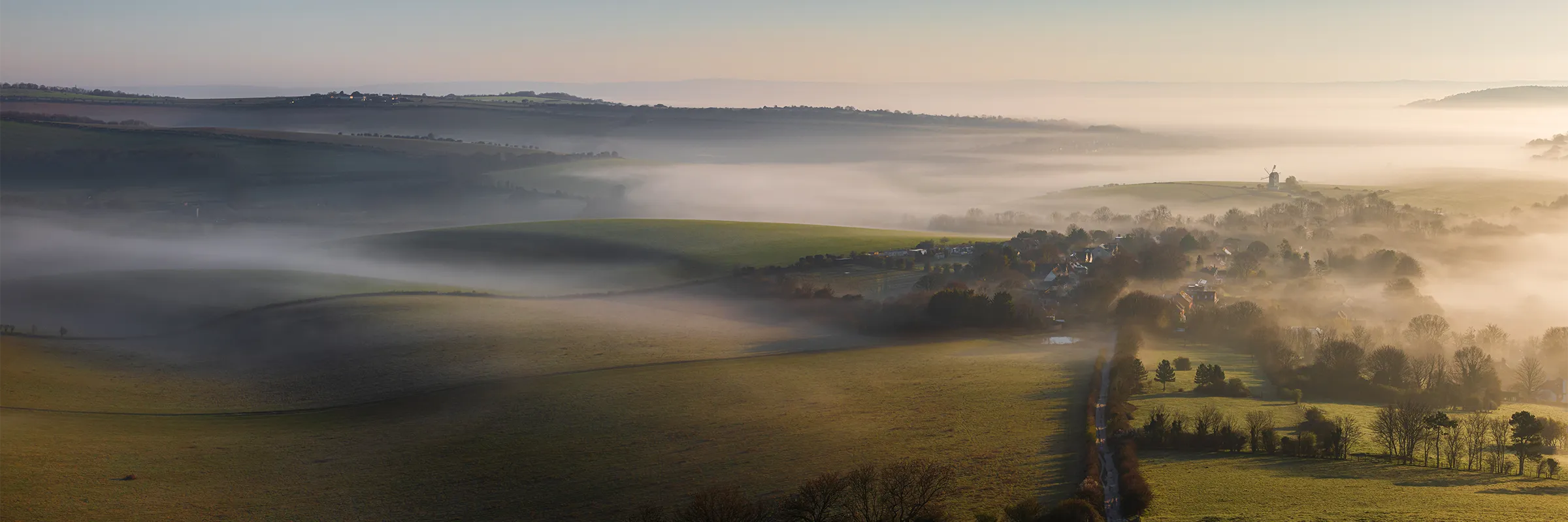 Rolling South Downs hills with low mist drifting through Kingston village in East Sussex at sunrise