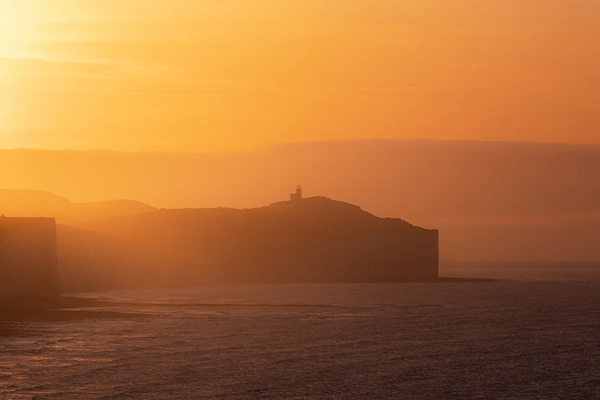 Belle Tout Lighthouse seen through warm coastal haze near Cuckmere Haven in East Sussex