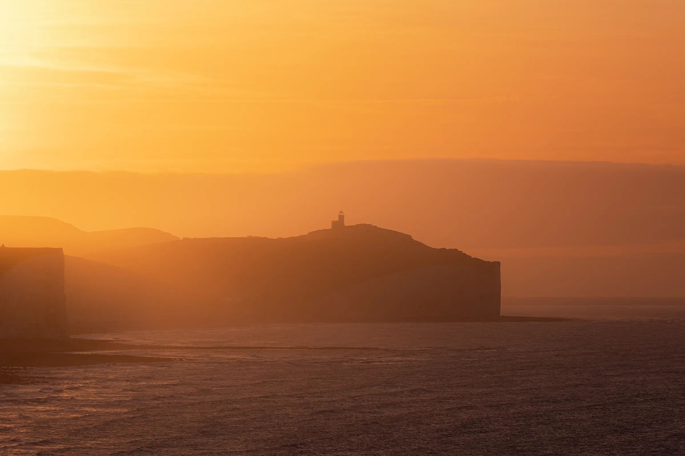 Belle Tout Lighthouse seen through warm coastal haze near Cuckmere Haven in East Sussex