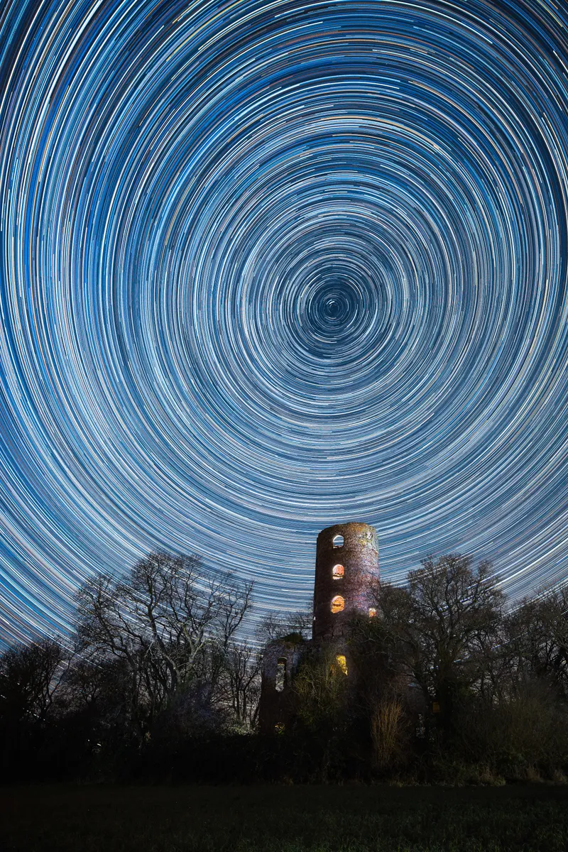 Star trails circling above Racton Ruins in West Sussex under a clear night sky
