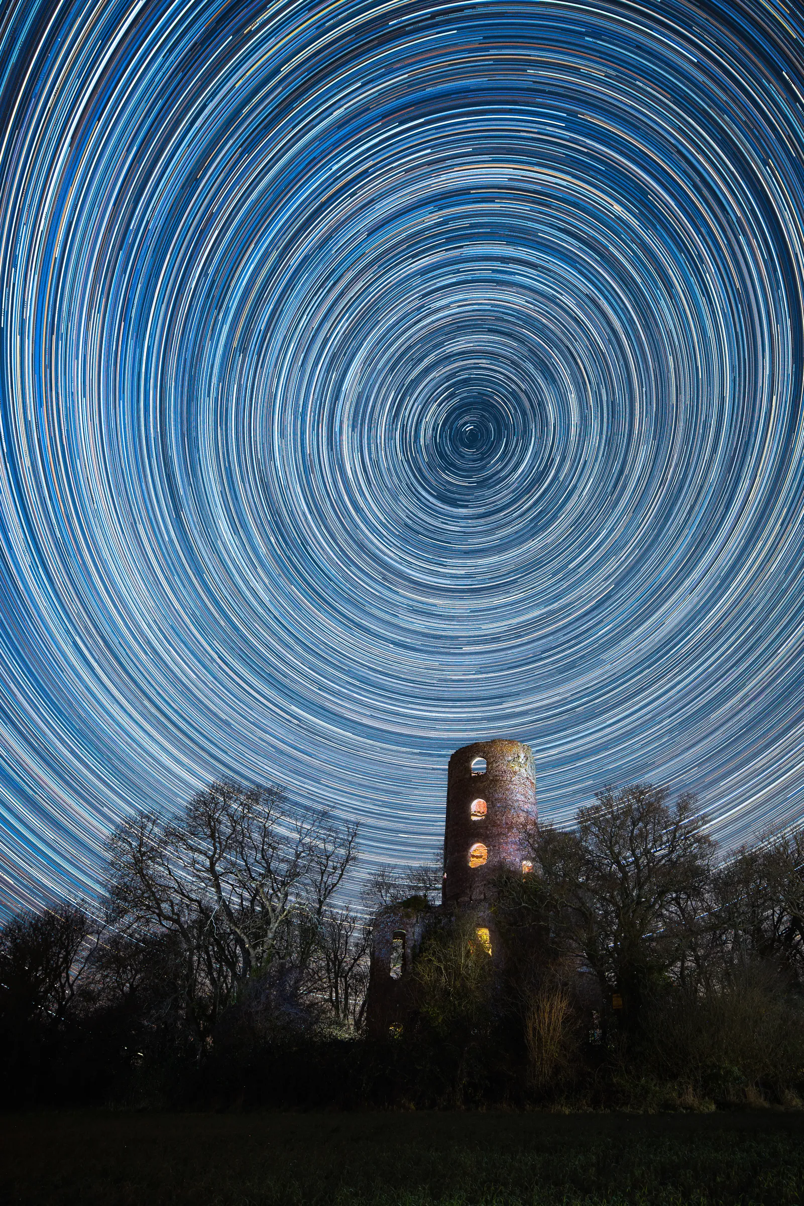Star trails circling above Racton Ruins in West Sussex under a clear night sky